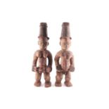 A pair of Ibo spirit figures, Nigeria, each with tall coiffure, signs of scarifications beneath