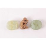 A Chinese light green carved jade pebble amulet pendant in the form of two tigers locked in combat
