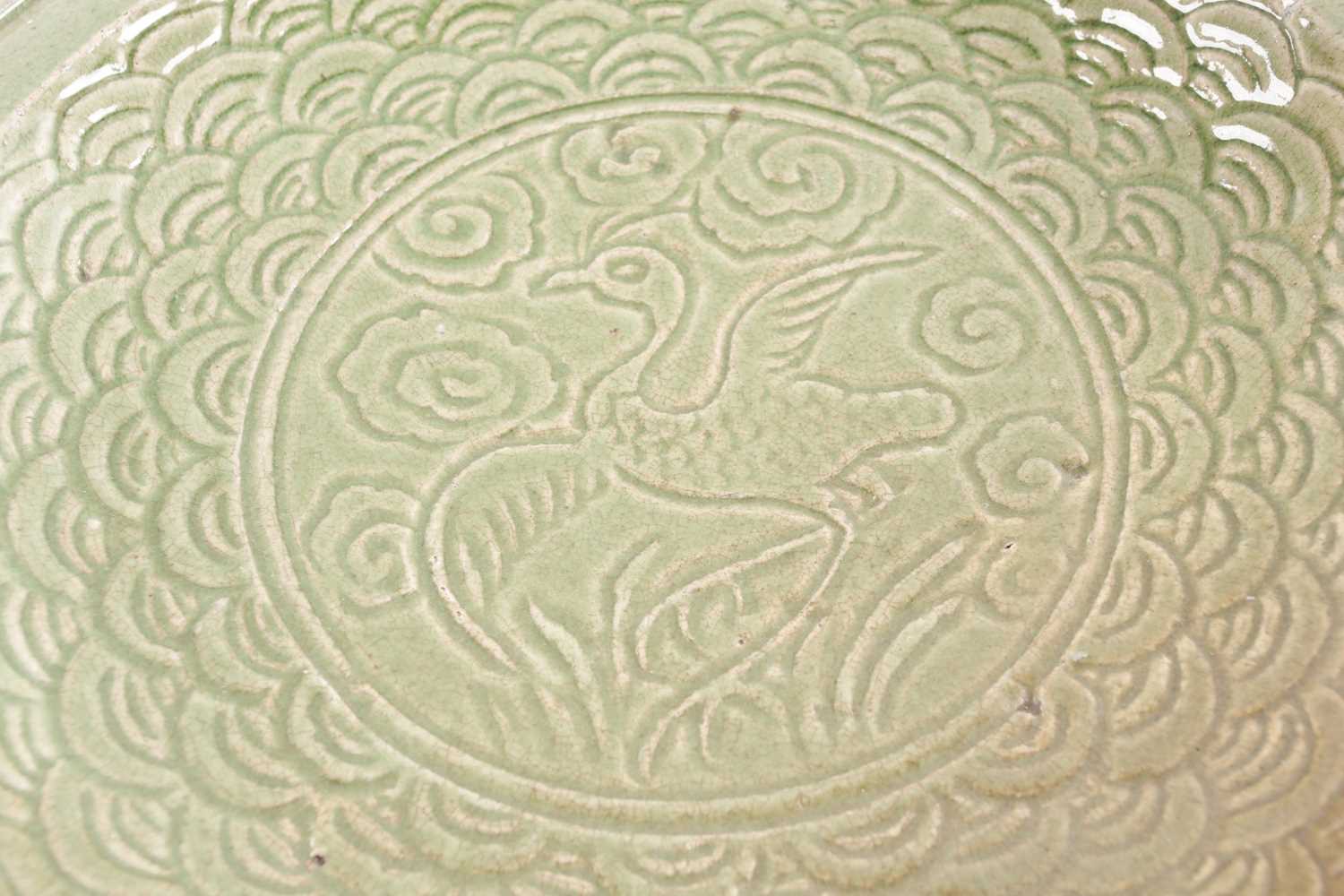 A circular celadon charger carved with a bird on a field of clouds within a stylized wave border - Image 4 of 5