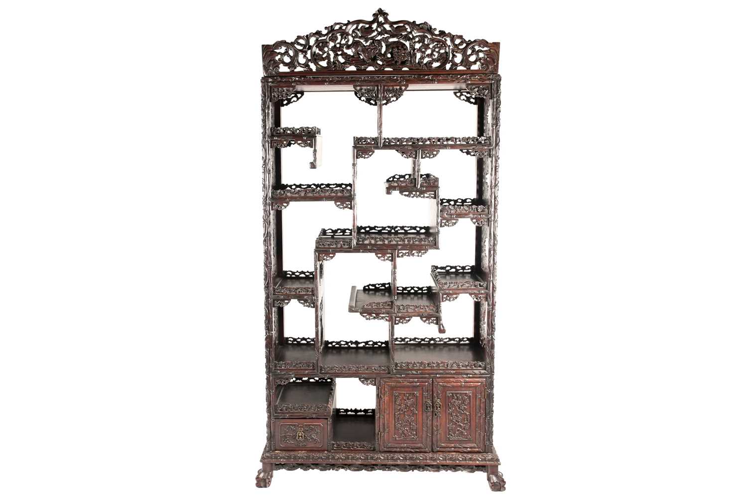 A Chinese hongmu open cabinet, early 20th century, carved throughout with Dogs of Fo, fruiting