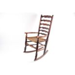 An early 19th century Lancashire "Cupid's Bow" ash ladder back rocking armchair with woven split