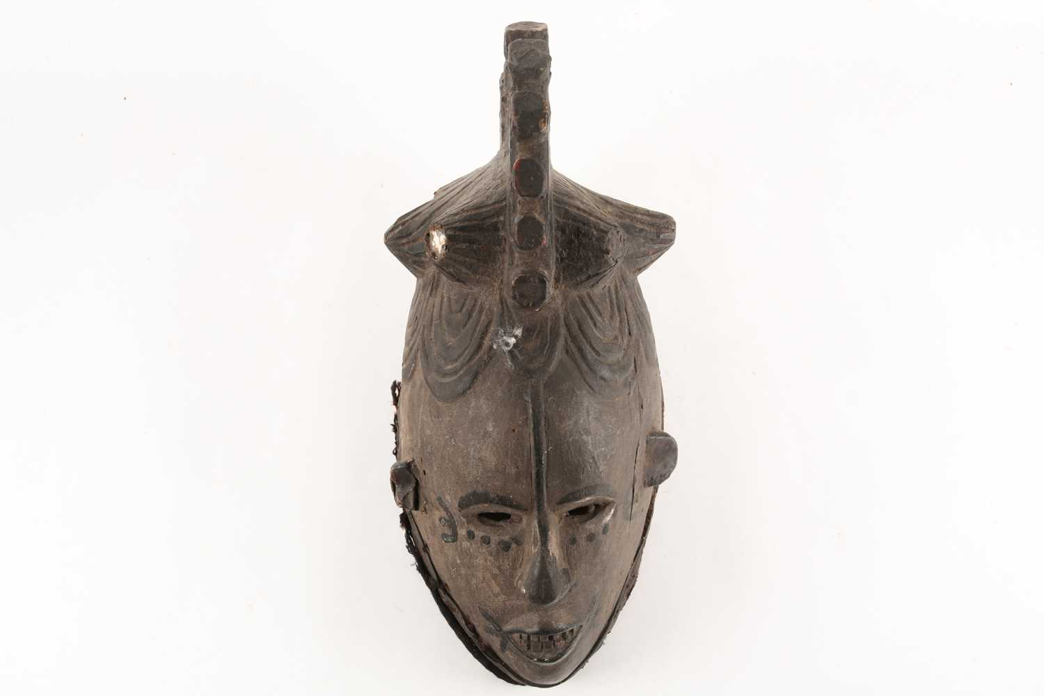 An Igbo Maiden Spirit mask, Agbogho Mmua, Nigeria, the headdress inset with two circular mirrors