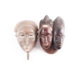 A Baule Janus mask, Mblo, Ivory Coast, each with inear carved coiffure, above a single braid on