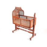 A mahogany and bergere rocking cradle, circa 1835/40, with lancet-arch canopy, rectangular sided and