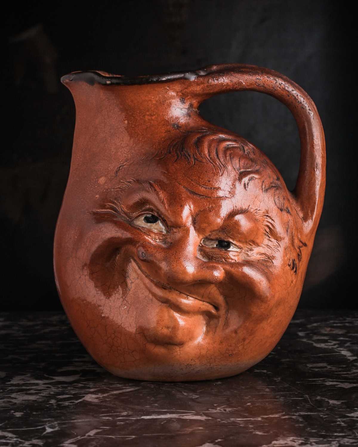 A Martin Brothers large double-sided stoneware face jug, dated 1899, modelled in relief to both