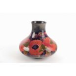 A William Moorcroft pottery vase, of squat form, tube lined in the Pomegranate pattern in red,