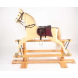 A carved and painted cremello rocking horse with horse hair mane, leather bridle and saddle on a