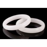 A pair of matching of white carved jade bangles of plain form. 8 cm diameter the slightly