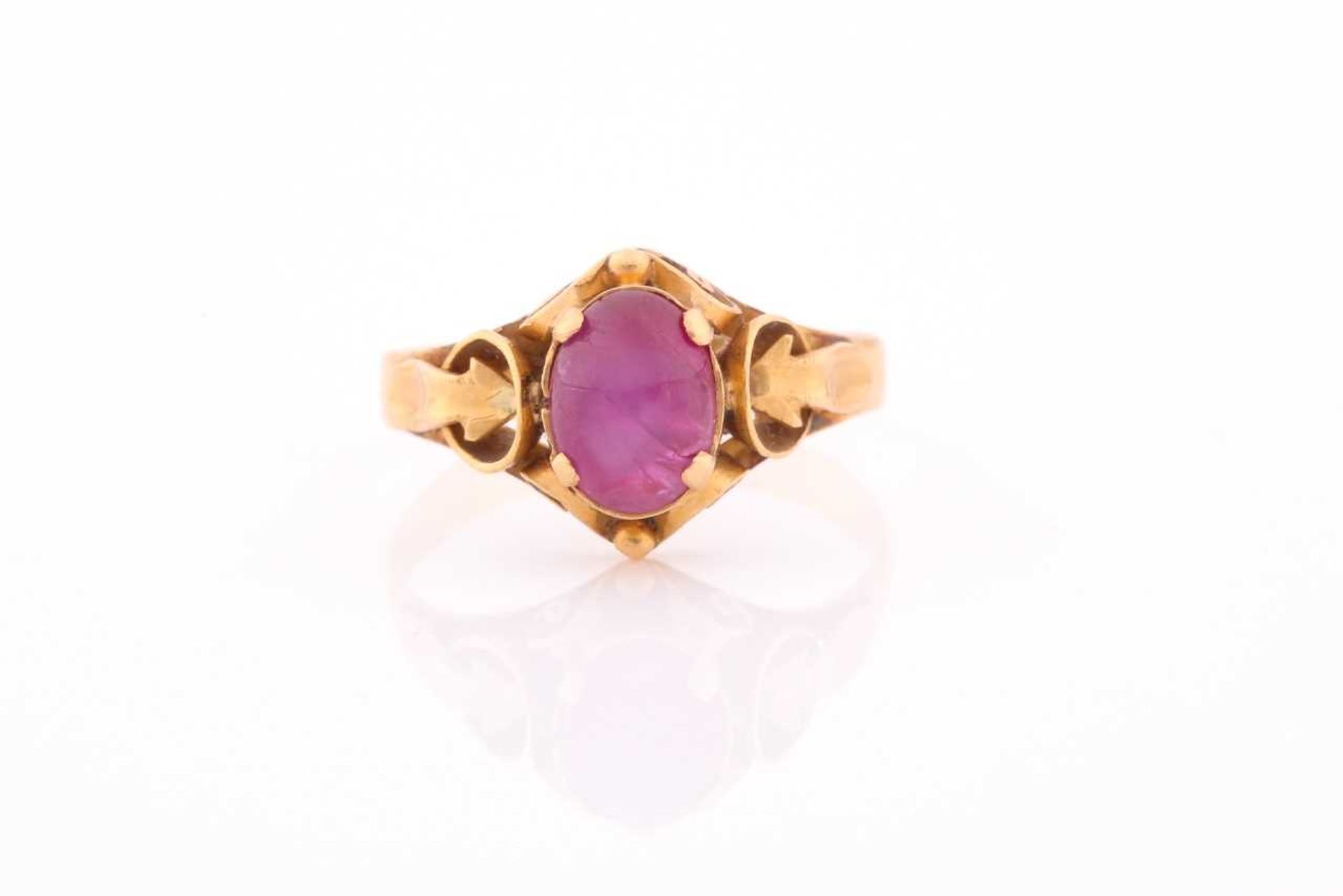 A yellow metal and ruby ring, set with a cabochon six-pointed star ruby, in an ornate antique-