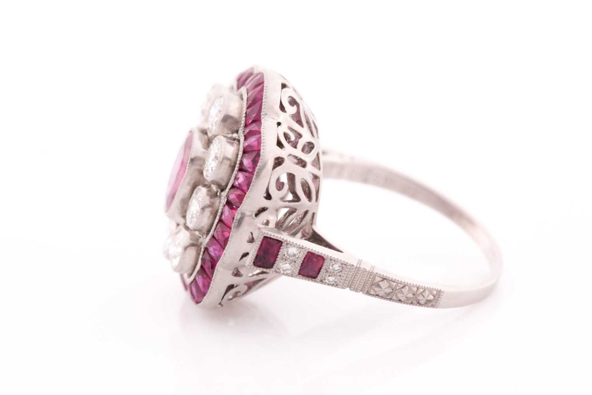 A platinum, diamond, and ruby ring, the stylised mount centred with a mixed oval-cut ruby within a - Image 3 of 5