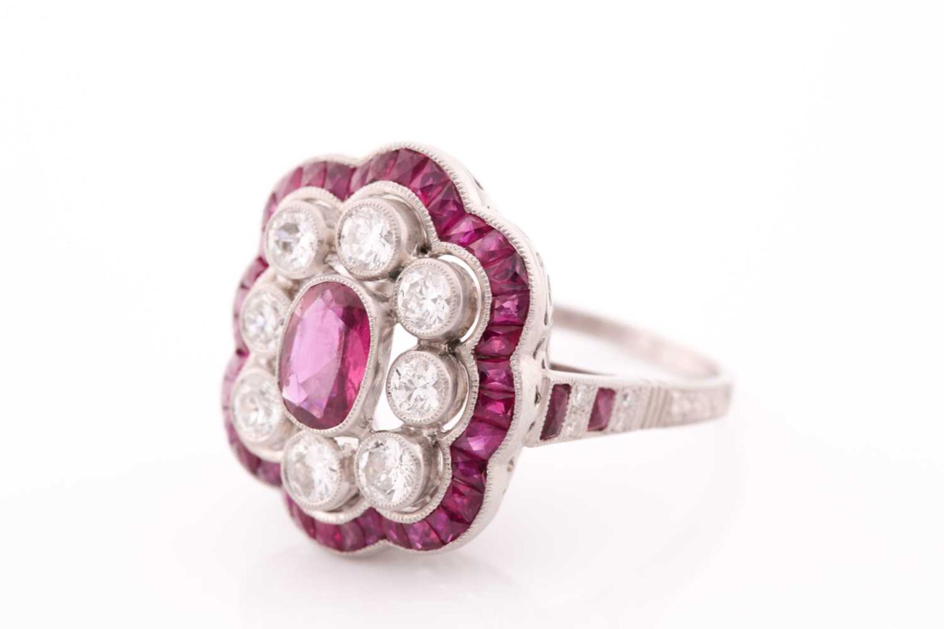 A platinum, diamond, and ruby ring, the stylised mount centred with a mixed oval-cut ruby within a - Image 2 of 5