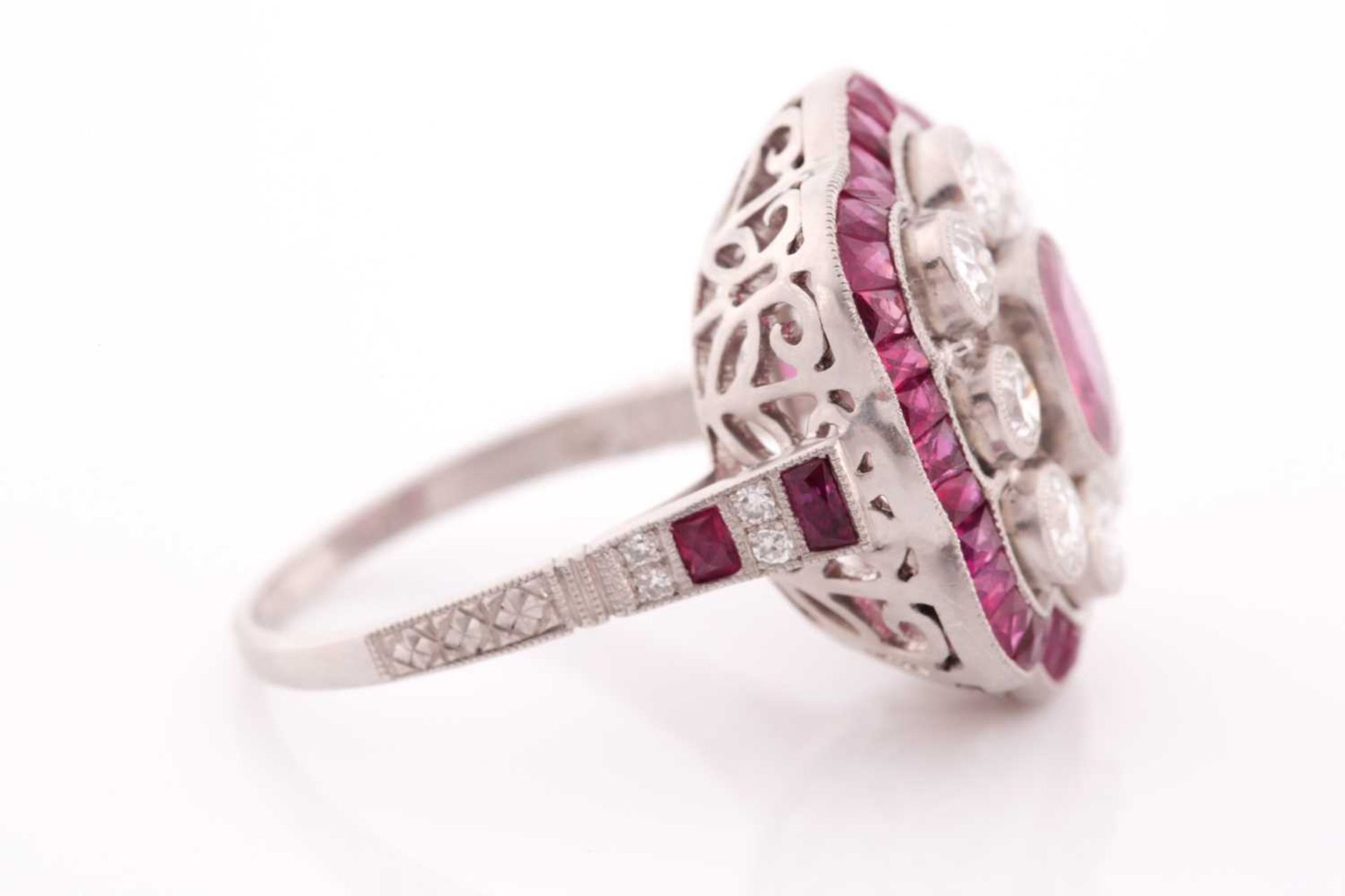 A platinum, diamond, and ruby ring, the stylised mount centred with a mixed oval-cut ruby within a - Image 4 of 5