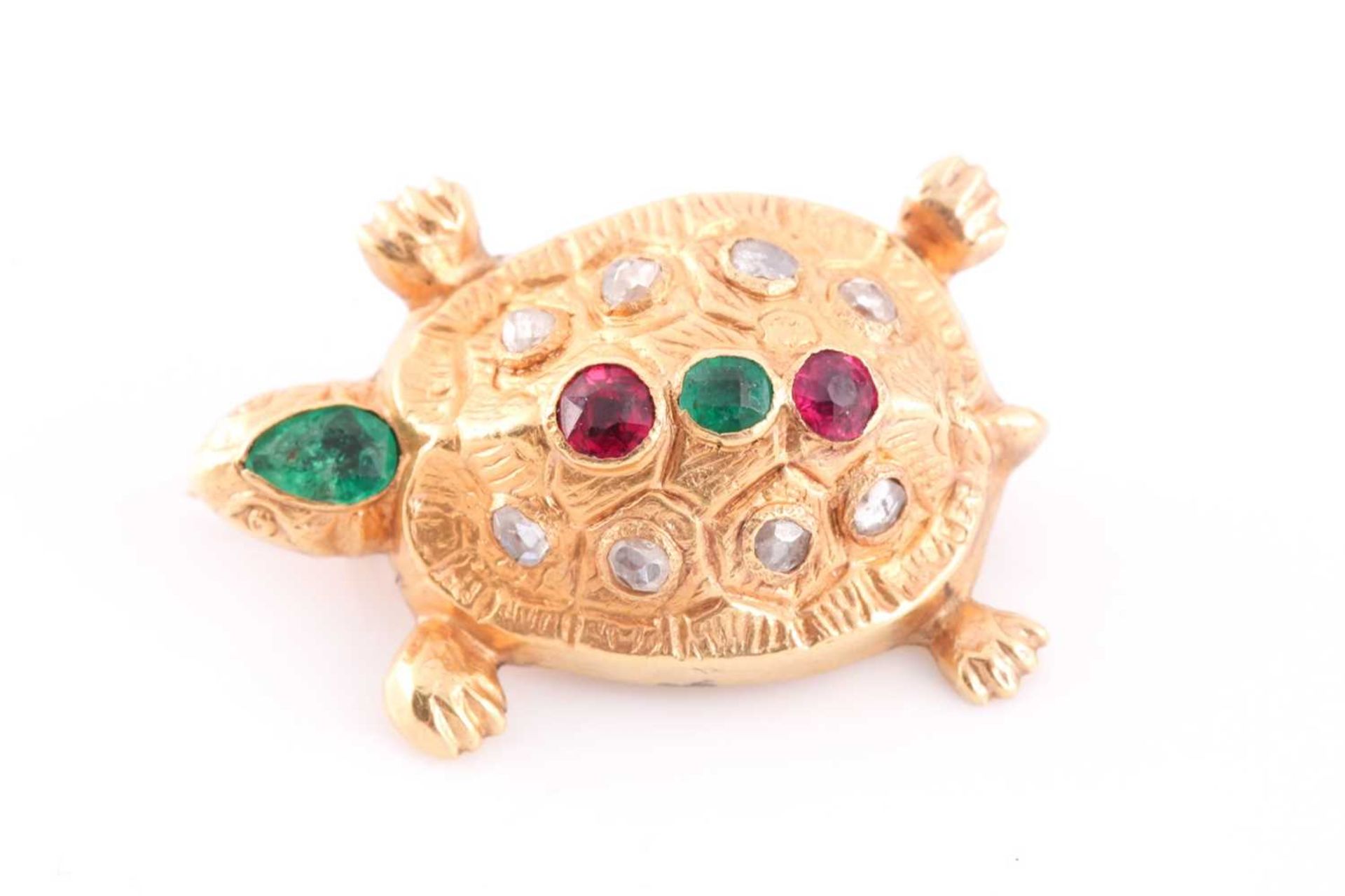 A yellow metal novelty brooch in the form of a turtle, inset with a pear-cut emerald to the head,