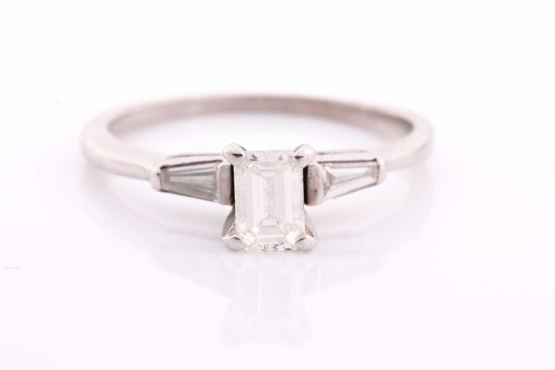 An 18ct white gold and diamond ring, set with an emerald-cut diamond of approximately 0.60 carats,