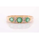 An early 20th century gold, emerald and diamond carved half-hoop ring, the three slightly