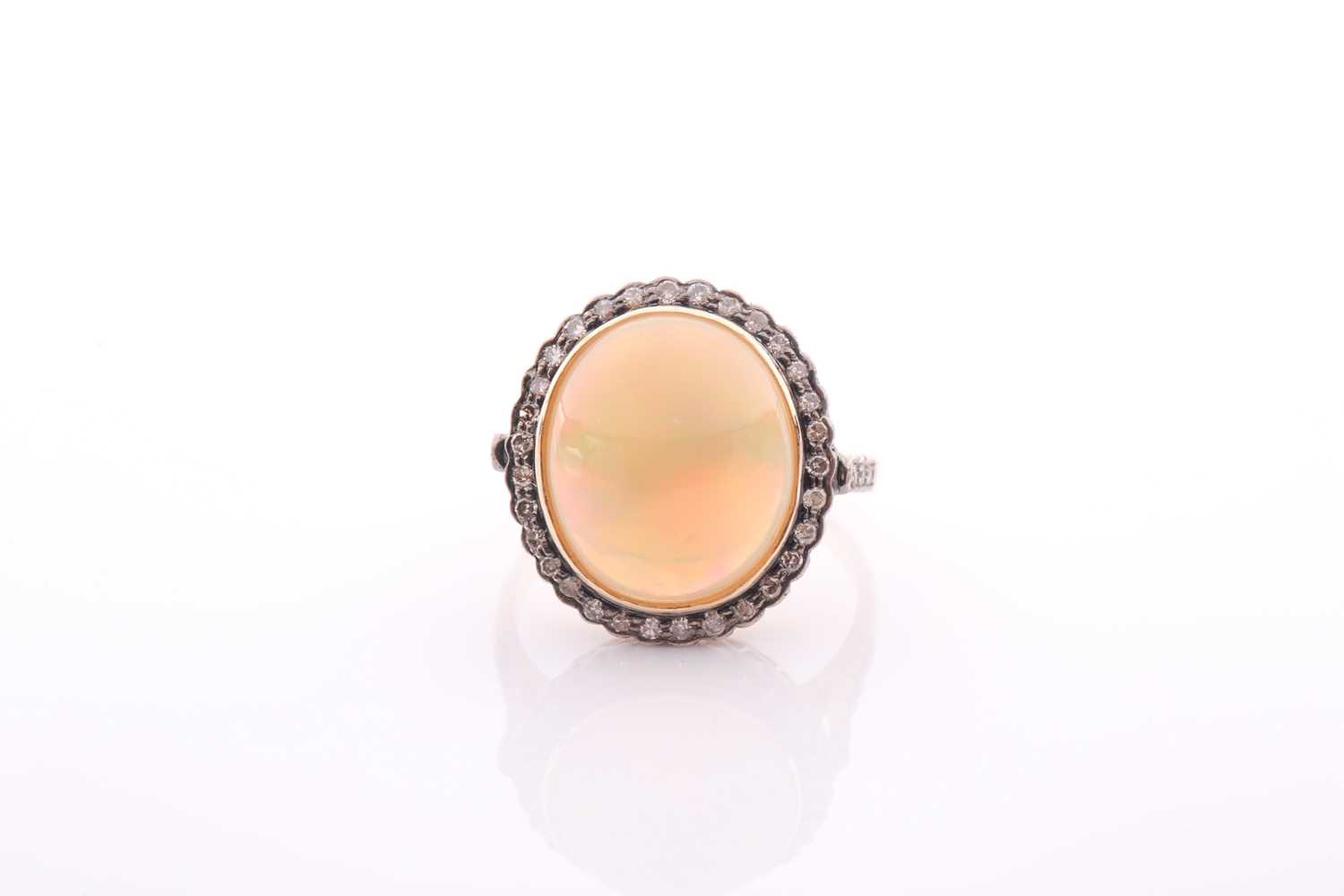 A modern opal and diamond oval cluster ring, centred with an oval cabochon Ethiopian ‘Melo’ opal,