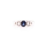 A sapphire and diamond ring; the central oval cut sapphire in four claw mounts, to diamond set