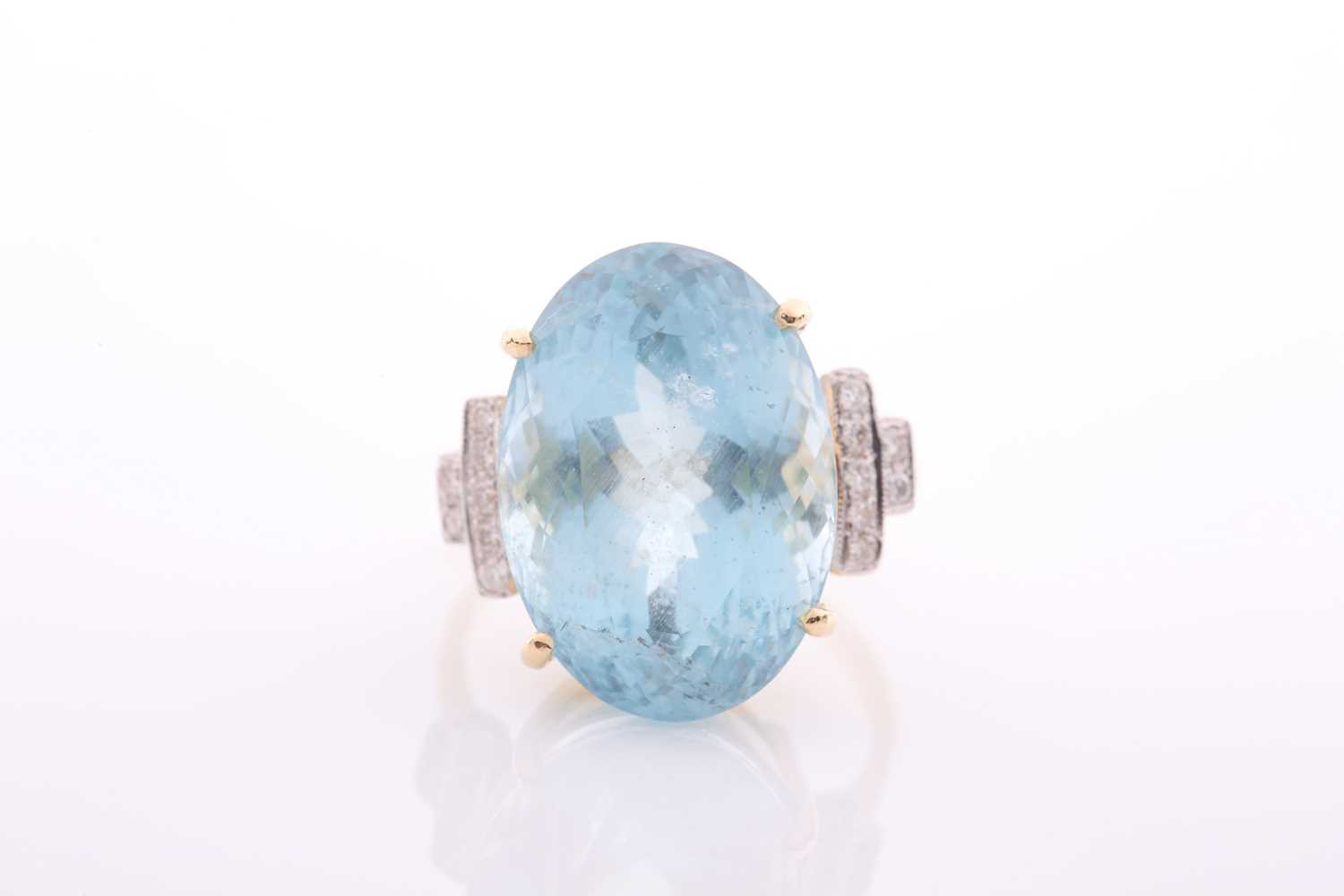 A modern aquamarine and diamond dress ring, centred with a large oval mixed-cut aquamarine,