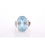 A modern aquamarine and diamond dress ring, centred with a large oval mixed-cut aquamarine,