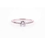 A single stone diamond ring, the round brilliant cut diamond in raised four claw mount above ten