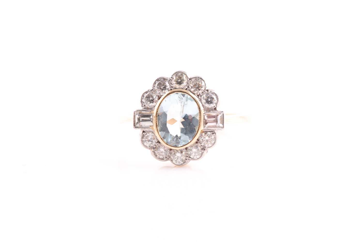 An aquamarine and diamond cluster ring; the oval cut aquamarine in rub over mount within a border of