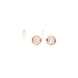 A pair of yellow metal and diamond solitaire earrings, each rubover set with a round brilliant-cut