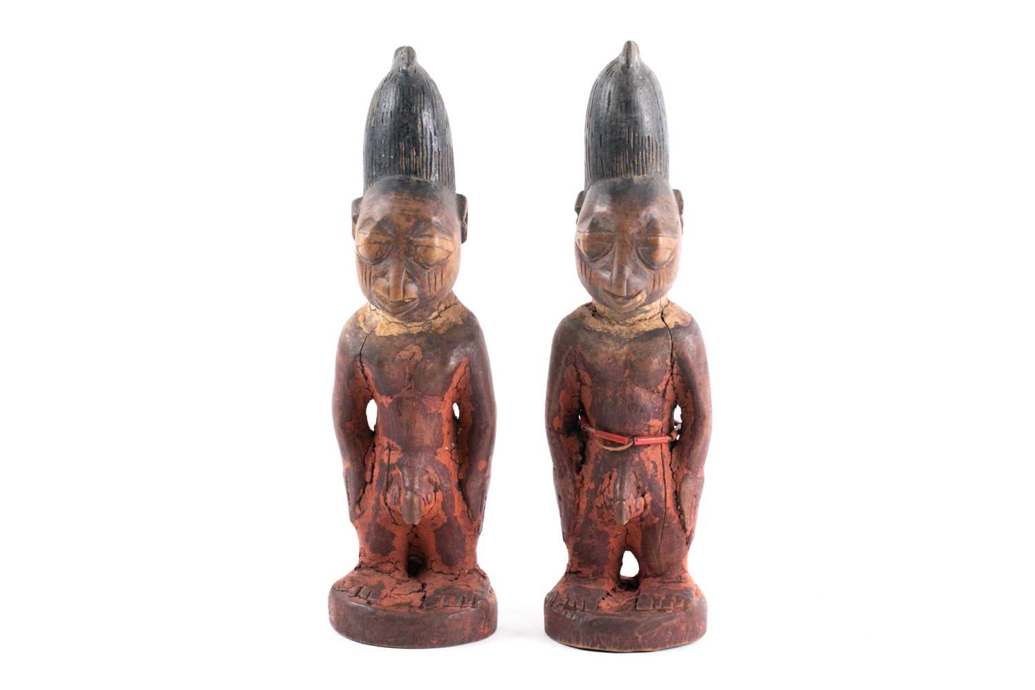 A pair of Yoruba twin male Ibeji figures, Nigeria, each with tall linear carved coiffure with traces