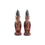 A pair of Yoruba twin male Ibeji figures, Nigeria, each with tall linear carved coiffure with traces
