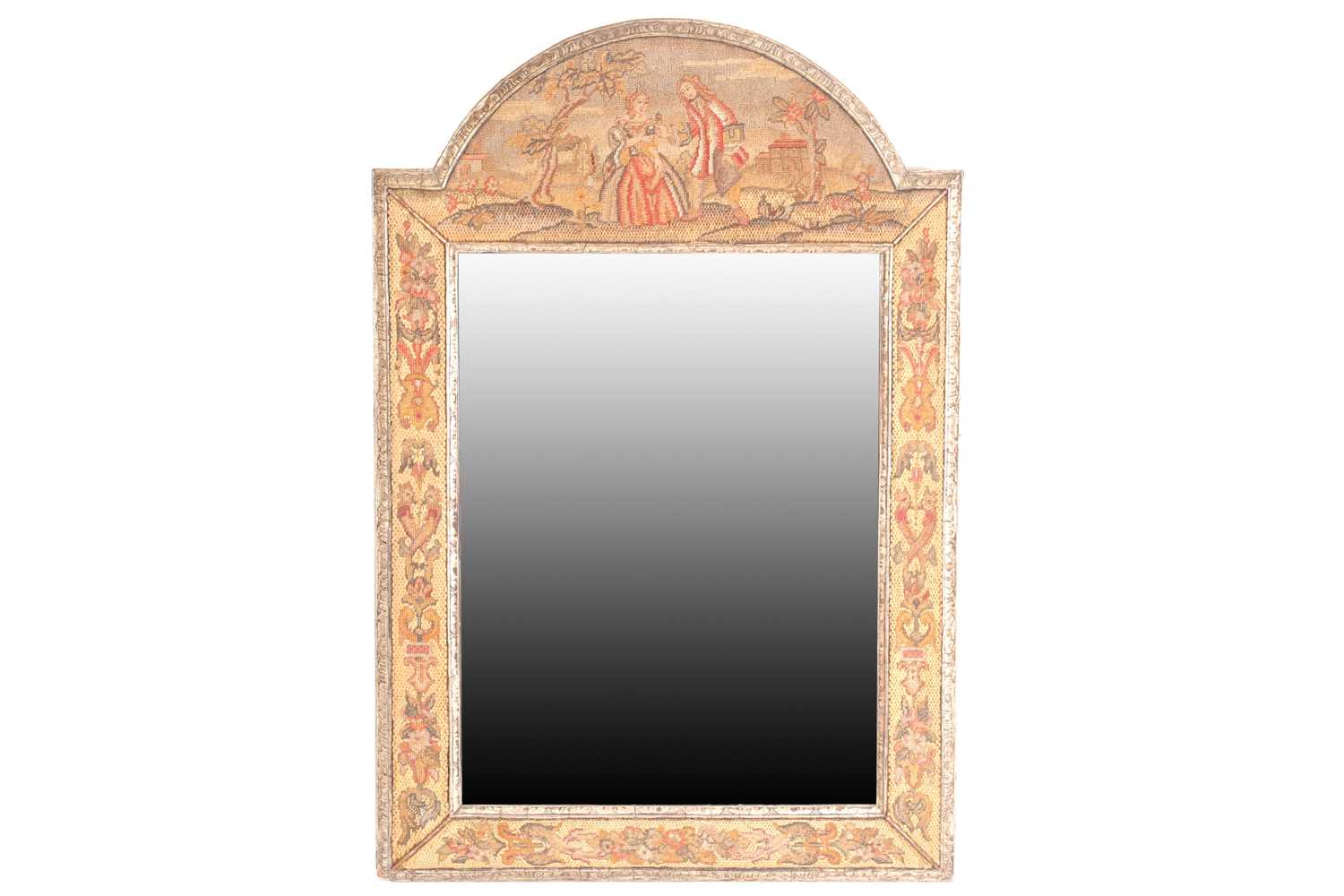 A Charles II style needlework wall mirror, the carved and silvered frame with embroidered scenes