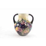 A Moorcroft Spring Flowers pattern twin handled vase, with tube-lined decoration on a pale green and