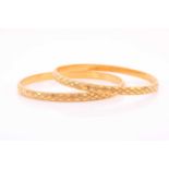 A pair of Indian yellow metal bangles, with bright-cut engraved decoration, unmarked, internal