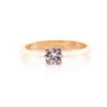 A solitaire diamond ring, the round brilliant cut diamond set in yellow metal with four square