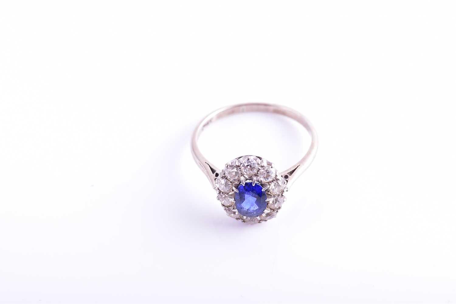 A diamond and sapphire cluster ring, set with a mixed oval-cut blue sapphire of approximately 1.10 - Image 2 of 4