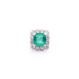 An emerald and diamond cluster ring; the rectangular cut-cornered emerald, in four claw mounts,