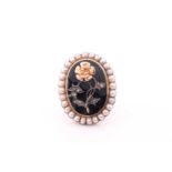 A late 19th century yellow metal, pearl, and black enamel mourning ring, inset with a floral design,