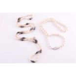 A white and black 'rice krispie' pearl necklace, fastened with a small yellow metal bow-shaped