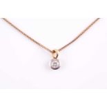 A single stone diamond and 18 carat gold pendant; the round brilliant cut diamond in a bi-coloured