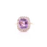 An amethyst and diamond cluster ring; the large cushion-cut amethyst in rub over millegrain mount