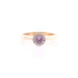 A pink sapphire and diamond cluster ring; the circular cut sapphire within a halo border of