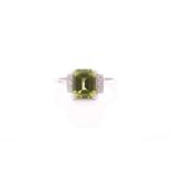 A platinum, diamond, and peridot ring, set with a mixed rectangular-cut peridot flanked with six