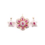 A ruby and diamond pendant and two further pendants; the principal flower head pendant set with a