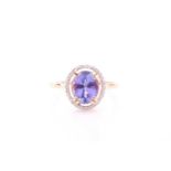 A 14ct yellow gold, tanzanite, and diamond ring, set with a mixed oval-cut tanzanite, within a