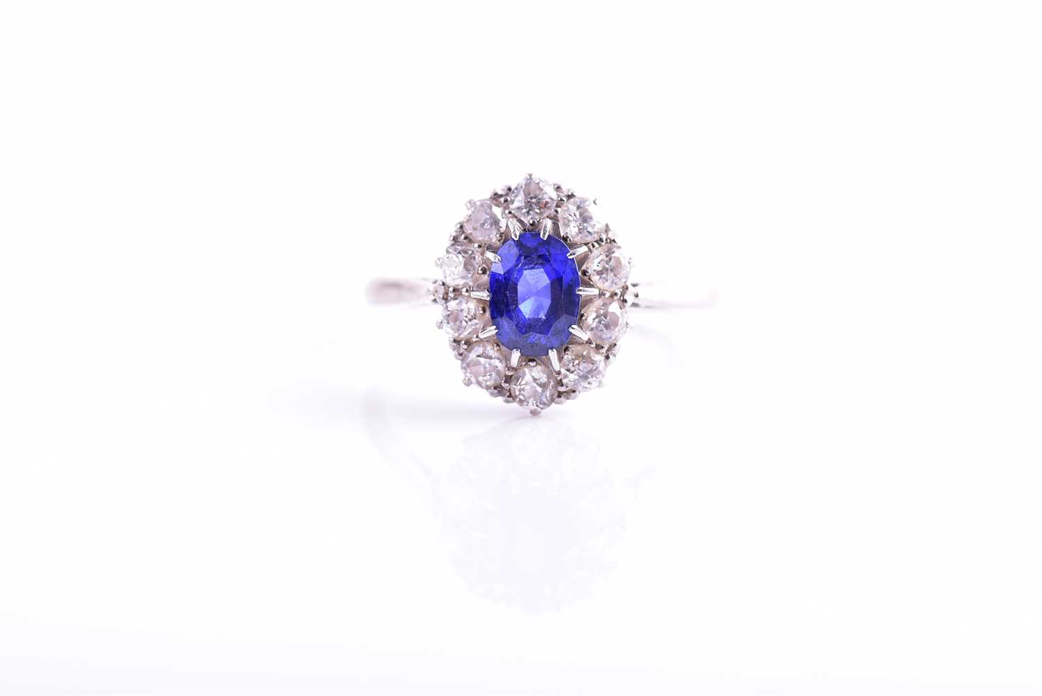 A diamond and sapphire cluster ring, set with a mixed oval-cut blue sapphire of approximately 1.10