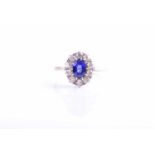 A diamond and sapphire cluster ring, set with a mixed oval-cut blue sapphire of approximately 1.10