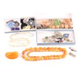 A small group of costume jewellery items to include an amber style (plastic) necklace, three