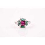 A ruby, emerald and diamond ring, the principal cushion-cut ruby in raised claw mount above a border