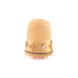 A yellow metal thimble, with applied filigree decoration, set with small diamonds, unmarked, in