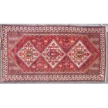 A 20th-century brick red ground Baktiari carpet in the Qashqai style with three diamonds on a