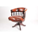 An early 20th-century tan hide upholstered hoop backed revolving desk arm chair with a reclining