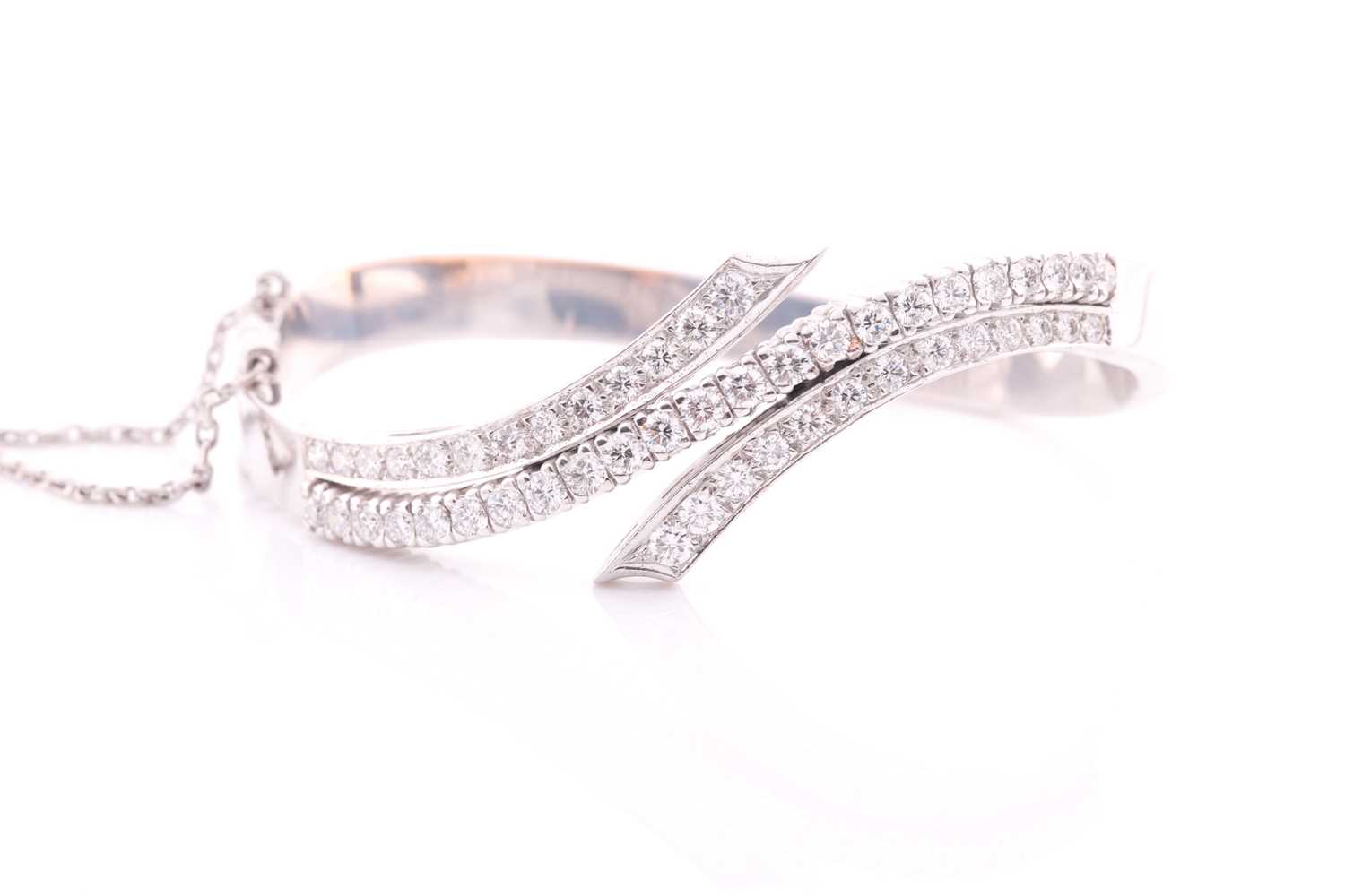 A diamond bangle of crossover design, inset with graduated round brilliant-cut diamonds of